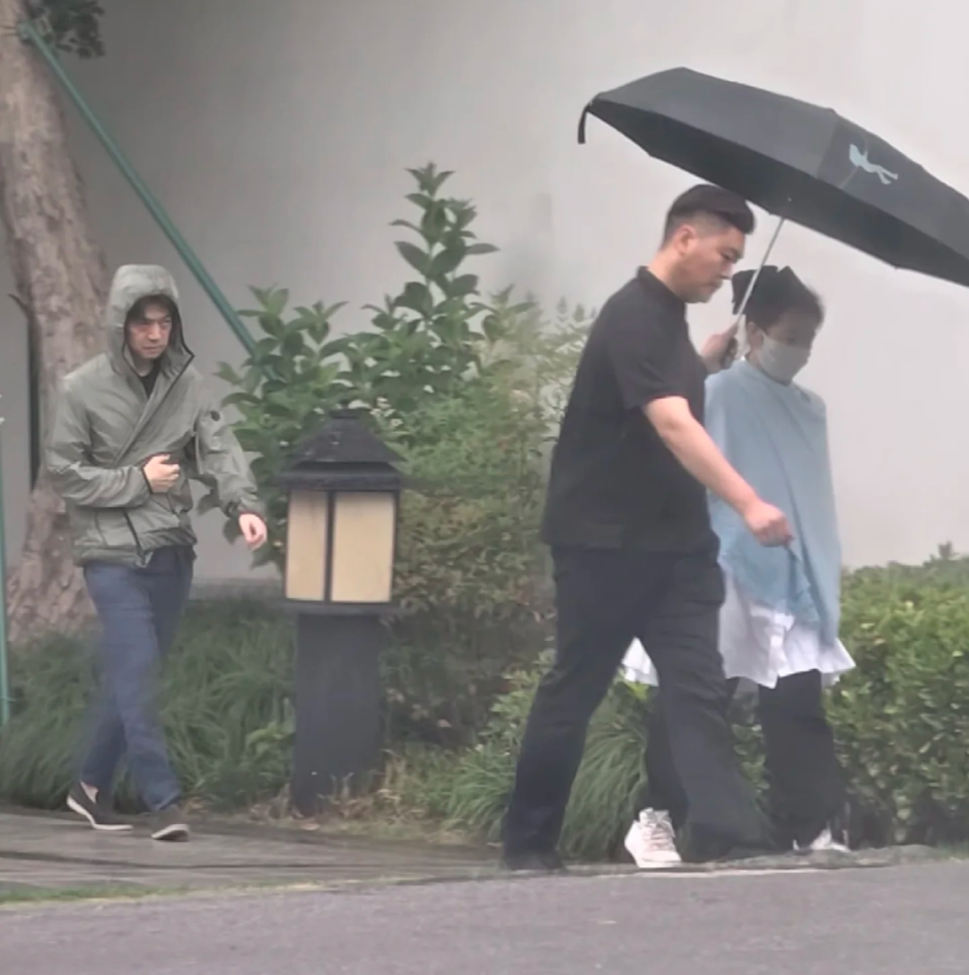 李健这么宠妻的吗？最近有人在酒店偶遇李健两口子，小细节让网友直呼嗑到了。 当天似乎天气不太好，黑衣保镖在前头给孟小蓓撑着伞，李健却在后面裹着衣服帽子狼狈淋雨，表情挺严肃的。  雨伞不大，这看起来是李健把伞让给老婆了。前头的孟小蓓身穿蓝色上