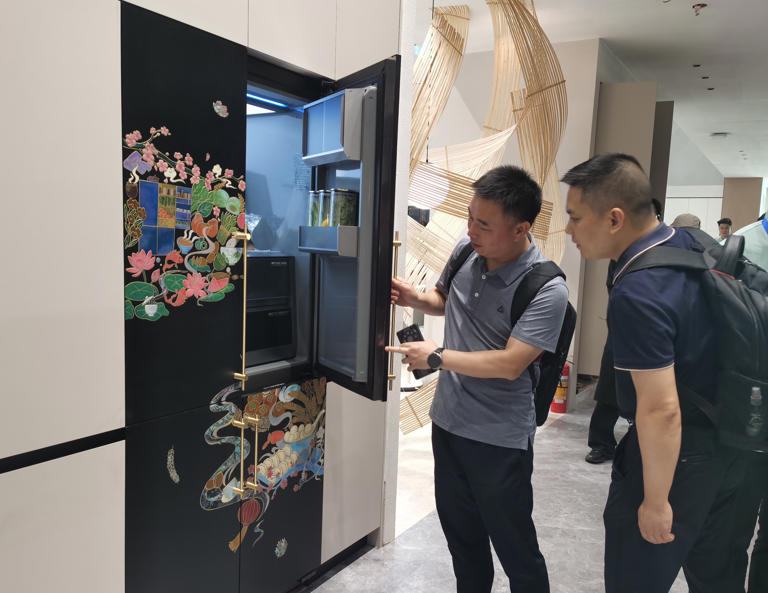 第27届中国建博会(广州)上，参展客商观看冰箱的手绘花纹。实习生 陈星摄