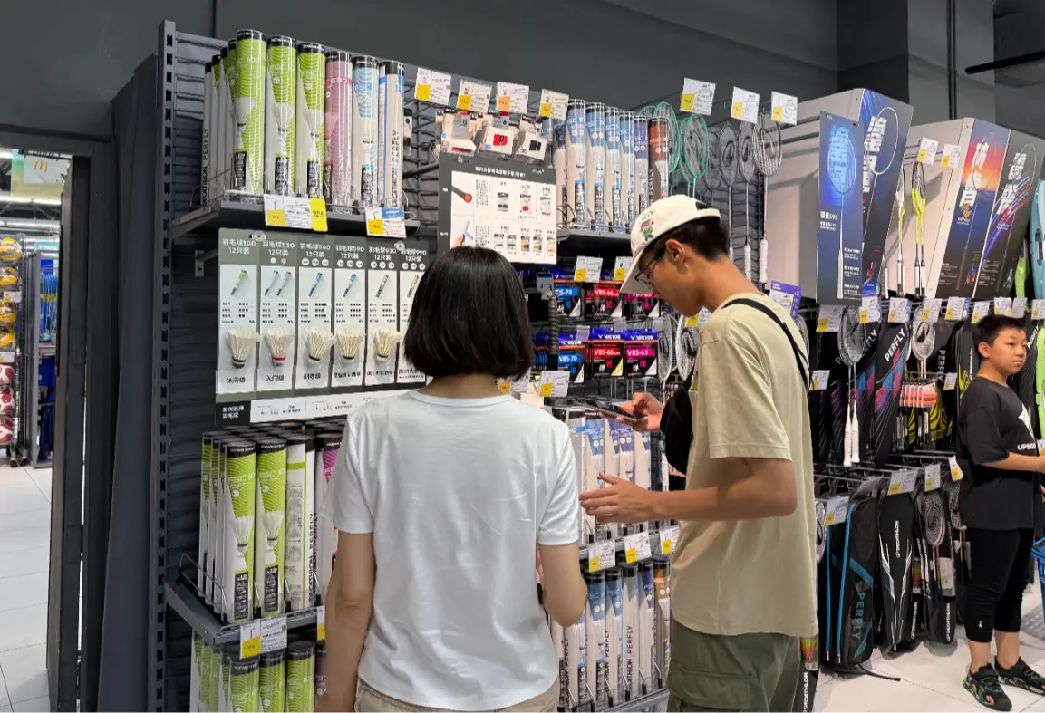 消费者正在对比选购羽毛球商品。