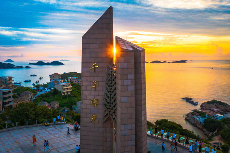 2021年7月17日，在浙江省温岭市石塘曙光园内，游客们在曙光碑下观看日出。徐伟杰拍摄